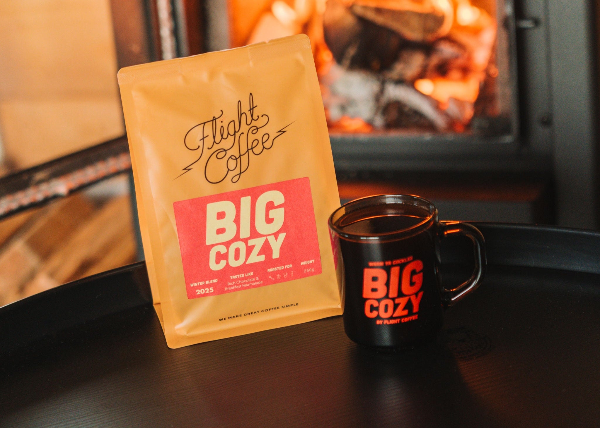 Flight Coffee Big Cozy coffee package and mug in front of a fireplace